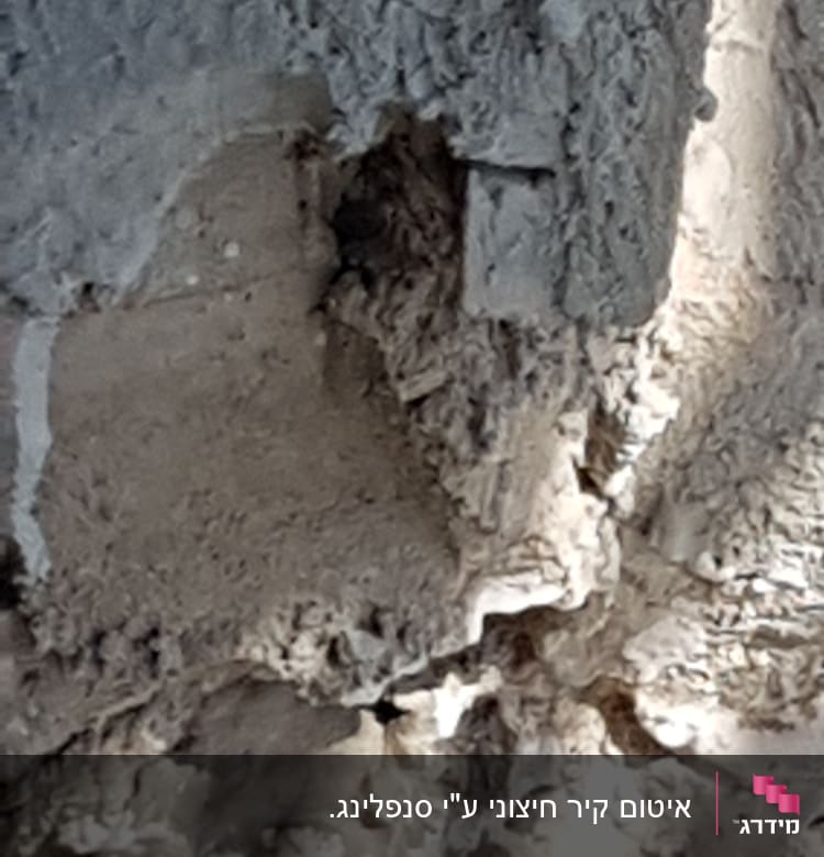 קיר בטון עם טיח מתקלף וחורים